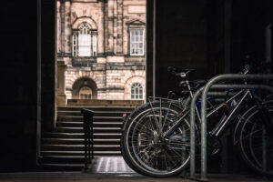 Student bikes on a rack with a view of Edinburgh University in the background.