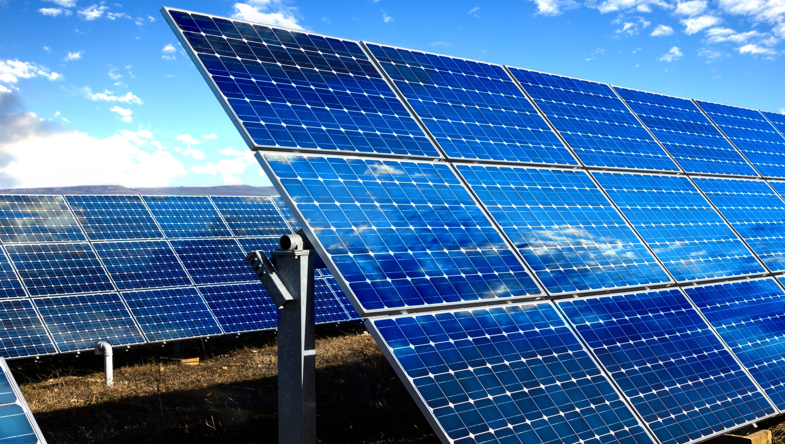 Rows of photovoltaic solar panels and blue sky with clouds