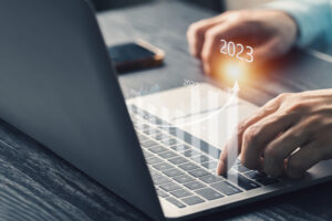 Man at laptop keyboard with upward vector and 2023 superimposed, tech investment trends
