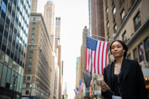 US expansion concept. Young black woman standing on Manhattan avenue beside Stars and Stripes
