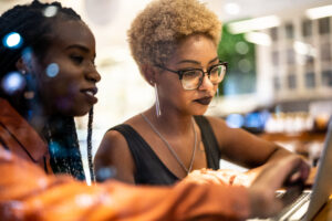 Scaling tech start-up concept. Two black businesswoman sharing computer screen