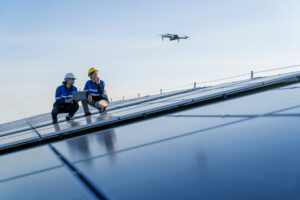 Two engineers checking solar panel farm with drone
