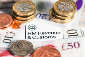 Corporation tax concept. Piles of coins surrounding HM Revenue & Customs letterhead